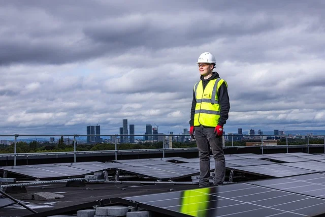 Pracownik instalujący panele fotowoltaiczne na dachu — audyt energetyczny i ESG dla firm